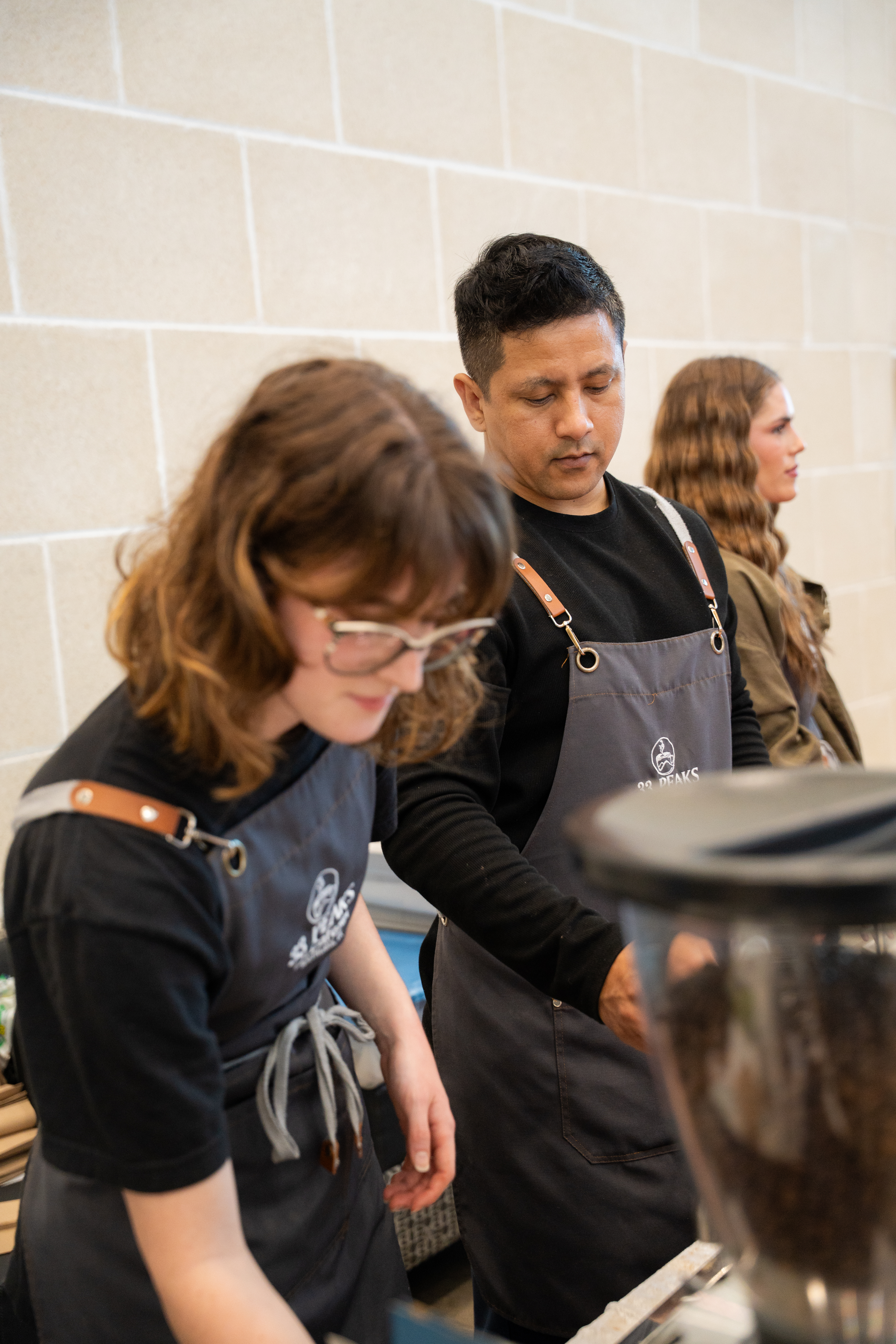 33 Peaks baristas in branded aprons crafting drinks behind the counter